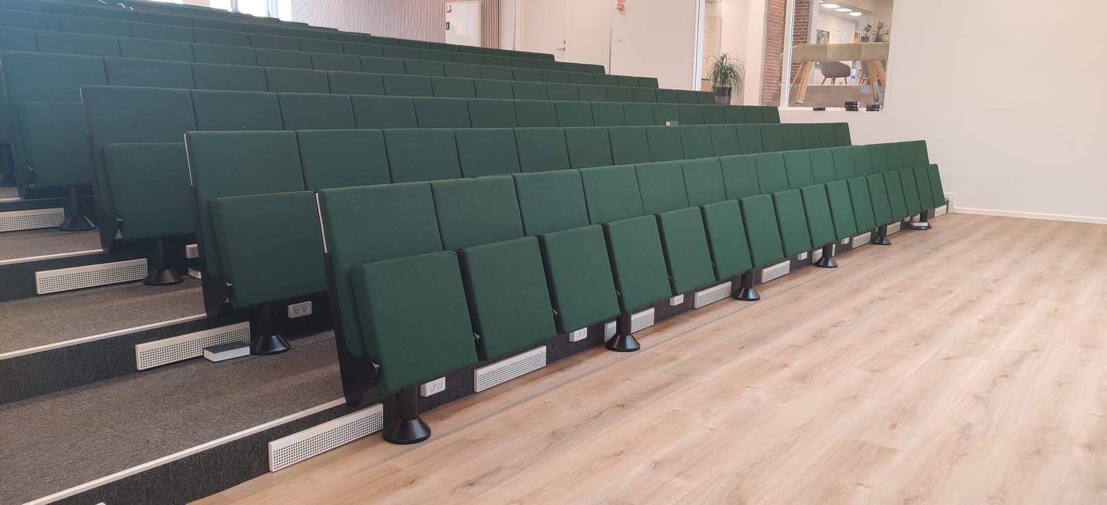 Grønne opklappede auditoriestole med stikkontakter og ventilationsriste på Vesterlund Efterskole