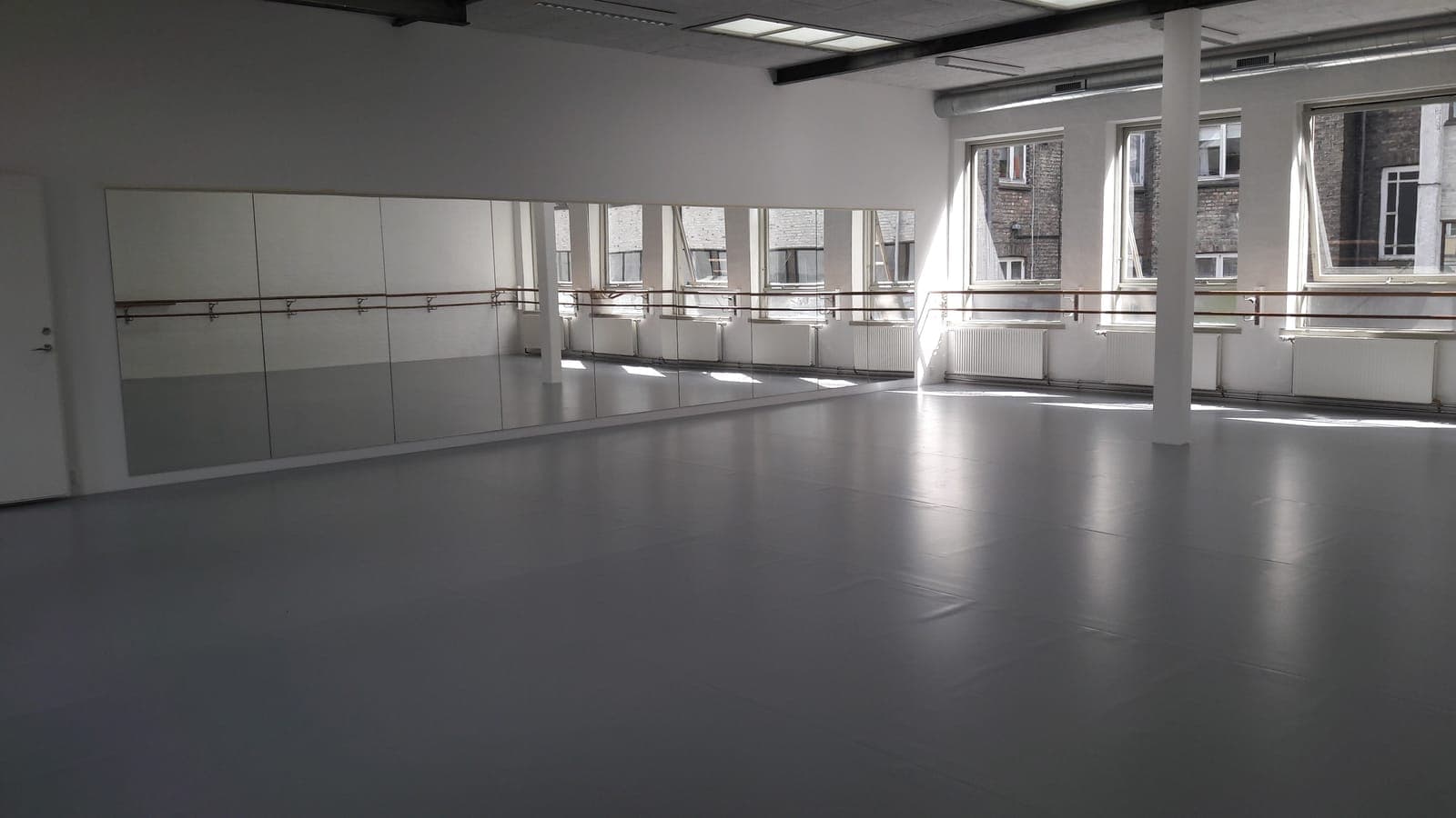 Grå dansevinyl i lys balletsal med spejlvæg og barrer hos Ballet Akademiet i Aarhus