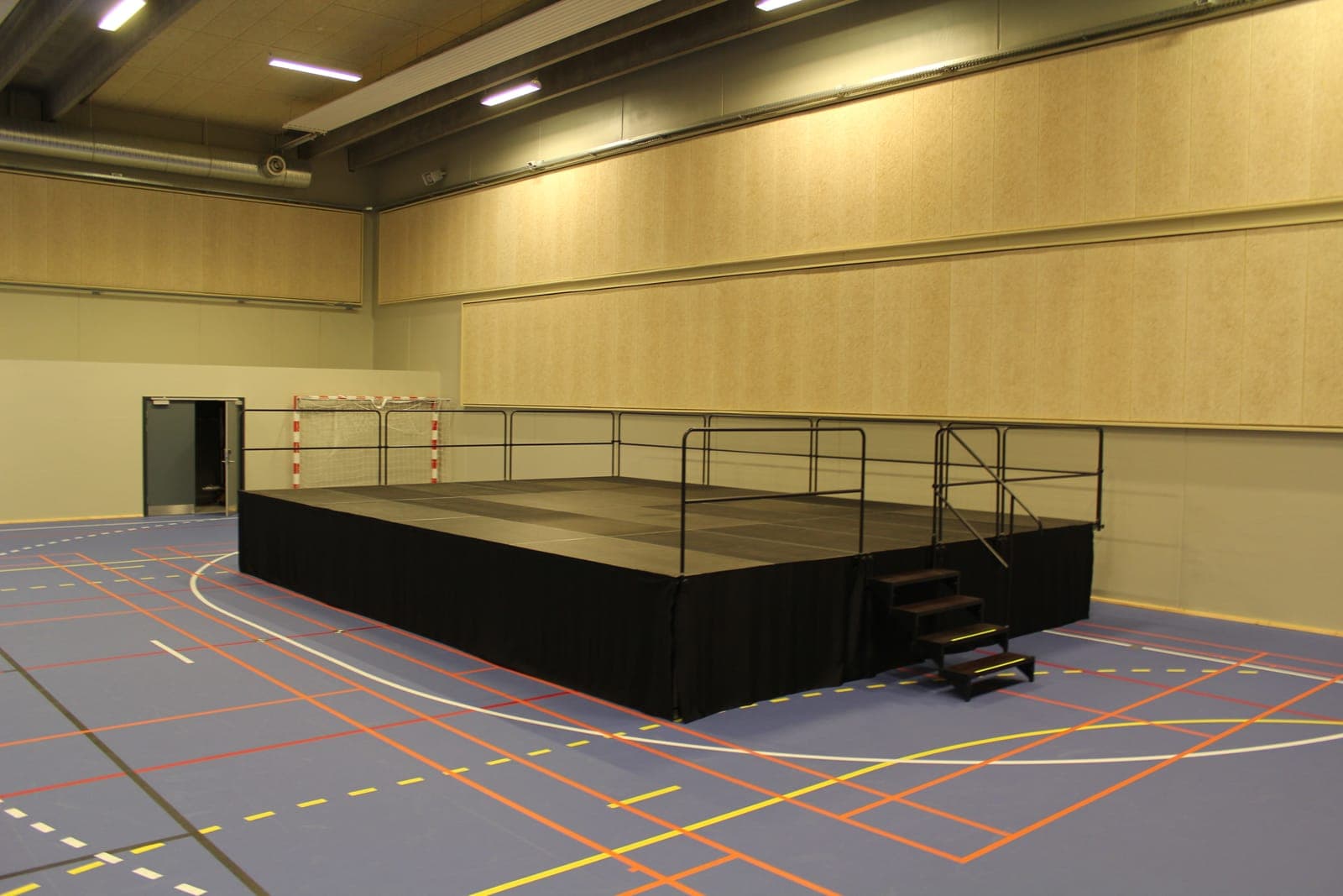 Scenepodie med sorte inddækningstæpper, gelændere og trappe på halgulvet i Skødstrup Hallen