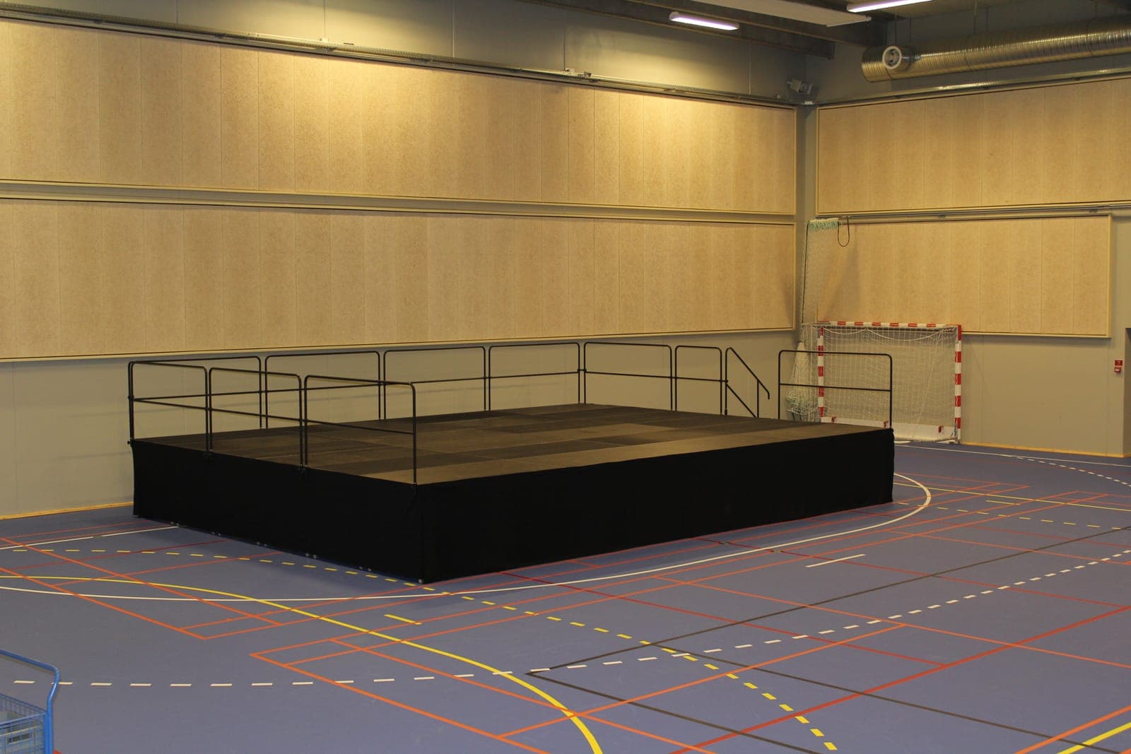 Scenepodie set fra scenefronten med gelænder langs sider og bagkant i Skødstrup Hallen