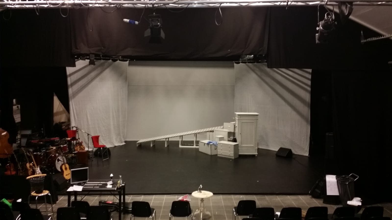 Sorte scenetæpper og hvidt bagtæppe indrammer scenen med lys i truss hos Grønlands Nationalteater