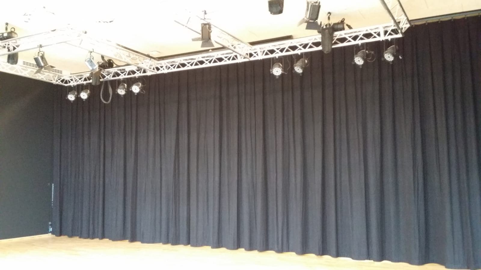 Sort scenetæppe trukket for i fuld bredde bag truss med spots på Silkeborg Gymnasium
