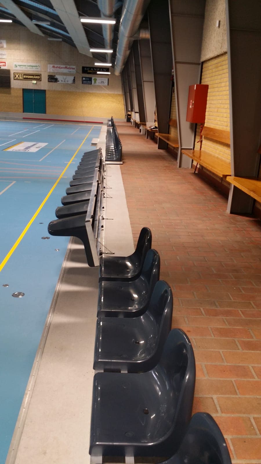 Række af sorte skalsæder monteret langs banekanten i Kolind Hallen