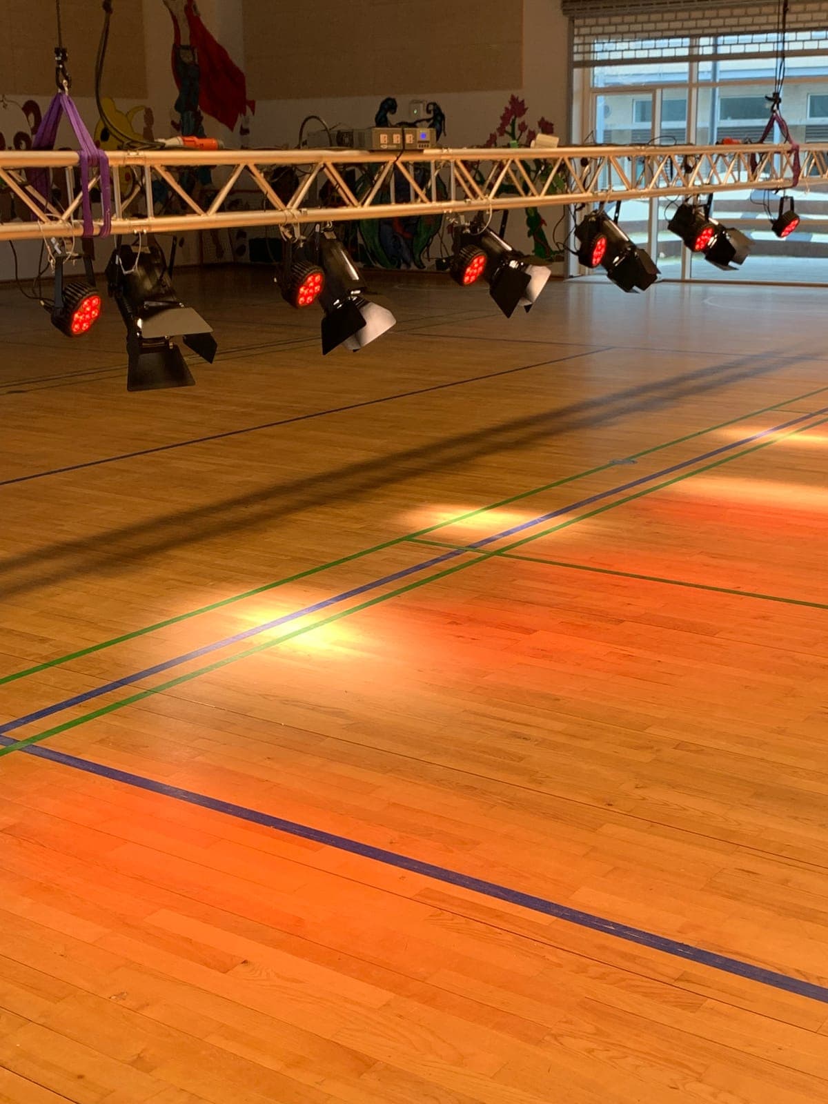 Tændte LED-spots på trussystemet kaster varmt lys over halgulvet på Strandgårdskolen i Ishøj