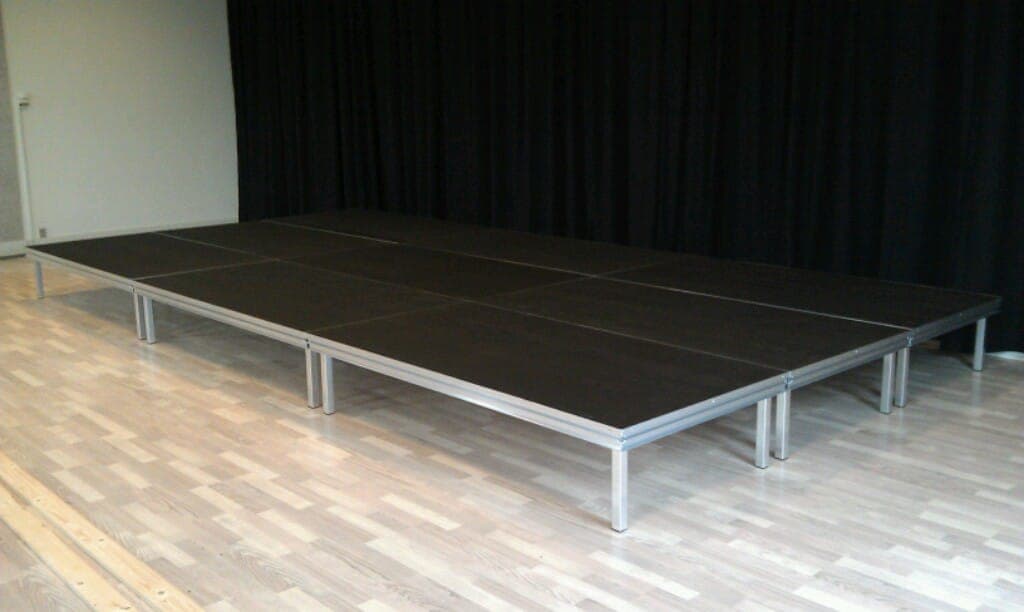 Scenepodier på aluminiumsben opstillet som samlet scene foran sort bagtæppe på Faxe Musikskole