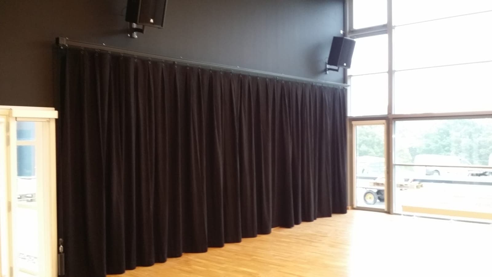 Mørkt scenetæppe i dybe folder på sort skinne langs væggen i salen på Silkeborg Gymnasium